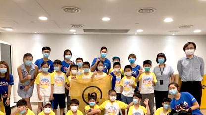 Intertek employees with students, holding a flag with the Intertek logo